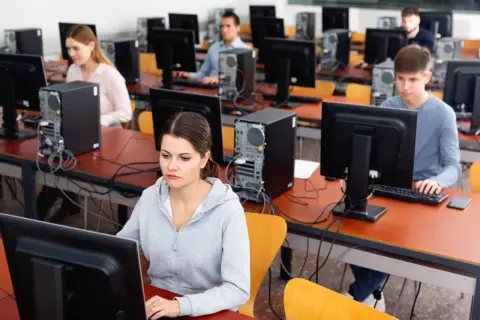 Uczniowie rozwiązują najtrudniejsze pytania na prawo jazdy w sali komputerowej.