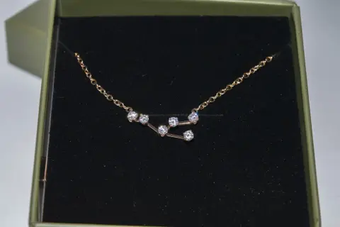 Colgante Tauro con circonitas brillantes en una caja verde.