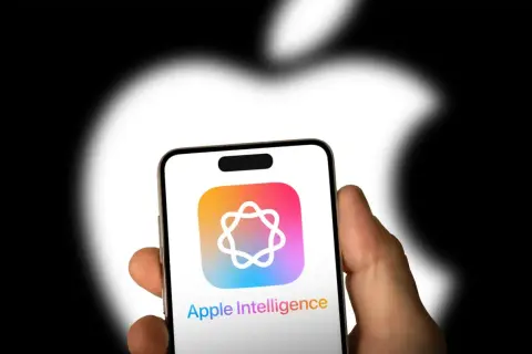 Dłoń trzyma iPhone'a z logo Apple Intelligence. Tło to rozmyte logo Apple.