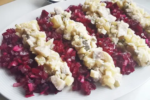 Pyszna sałatka śledziowa z burakiem, ziemniakami i majonezem, podana na białym talerzu.