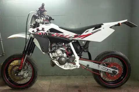 Husqvarna SMS 125 w białej odsłonie z czerwono-czarnymi grafikami, gotowy do jazdy po mieście i torze.