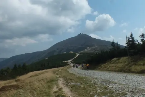 Szlak na Śnieżkę z Szklarskiej Poręby. Grupa turystów wędruje kamienistą ścieżką pod górę, w kierunku szczytu.