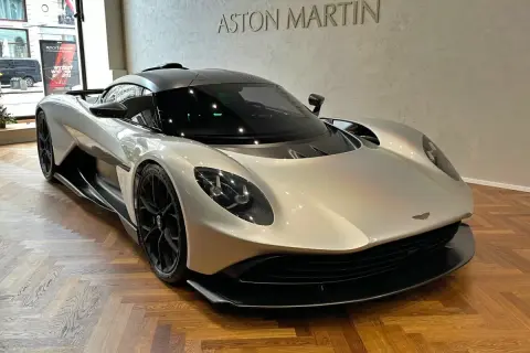 Srebrny Aston Martin na drewnianej podłodze. Zastanawiasz się nad aston martin cena?