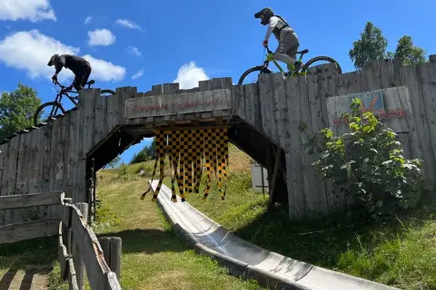 Två cyklister på en träbro i en bikepark i Tyskland. En perfekt plats för en äventyrlig semester.