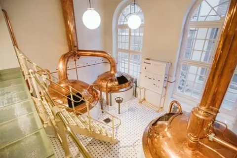 Cata de cervezas Zaragoza: Cobre brillante y escaleras metálicas en una cervecería tradicional.