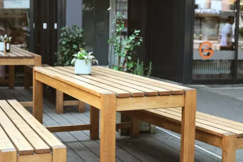 Ensemble de mobilier d'extérieur en bois, table et bancs, dont le traitement met en valeur la beauté naturelle du bois.