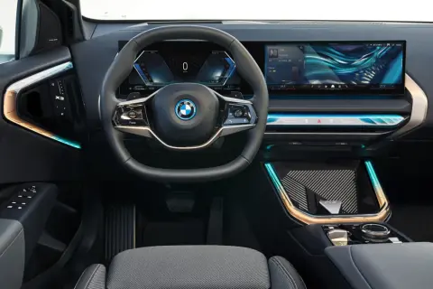 Interni moderni con volante, cruscotto digitale e ampio schermo per il sistema infotainment. Dettagli luminosi e finiture eleganti.