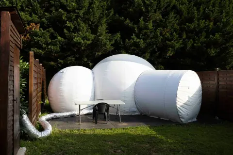 Une bulle gonflable blanche, prête pour une nuit insolite en Île-de-France, est installée dans un jardin verdoyant.