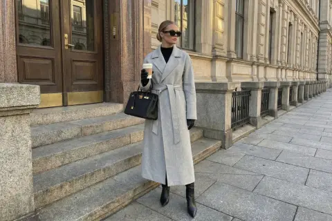 Elegancki szary płaszcz z paskiem, połączony z czarnymi kozakami i torebką, tworzy stylowy look.