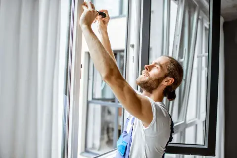 Técnico ajustando un marco de aluminio para cambiar el cristal de una ventana.