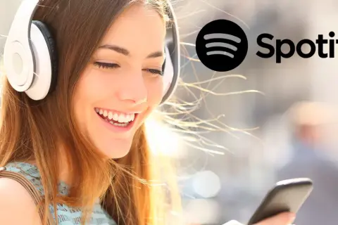 Uśmiechnięta dziewczyna w słuchawkach słucha muzyki na Spotify. Dowiedz się, jak zmienić nazwę użytkownika na Spotify.