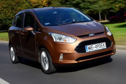 Brązowy Ford B-Max jedzie po drodze, za nim drzewa w jesiennych barwach.