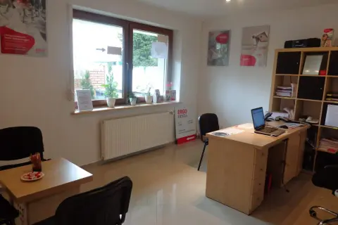 Biuro z biurkiem, laptopem, krzesłami i oknem.