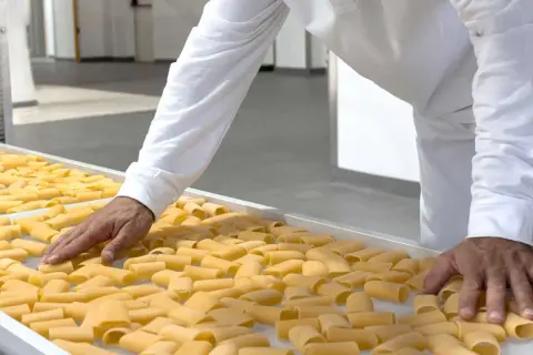 Mani che controllano paccheri freschi, pronti per le migliori cavedano ricette.