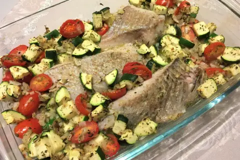 Filet de lieu noir rôti avec tomates cerises et courgettes coupées en dés, assaisonné d'herbes.