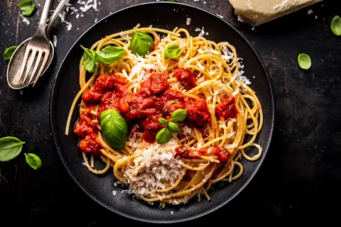 Talerz spaghetti z sosem pomidorowym, parmezanem i bazylią.