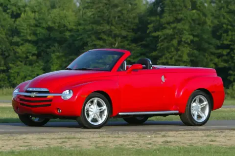 Czerwony Chevrolet SSR z otwartym dachem, gotowy na letnią przejażdżkę pośród zieleni.