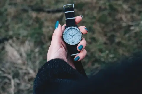 Dłoń z turkusowymi paznokciami trzyma zegarek z czarną bransoletką. Zastanawiasz się, czym wyczyścić bransoletkę od zegarka?