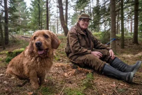 En man i skogen vilar bredvid sin trogna diabetes hund.