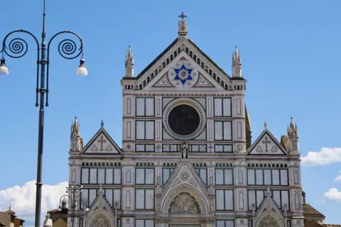 Fasada katedry Santa Maria del Fiore we Florencji, ozdobiona mozaikami i rzeźbami, lśni w słońcu.