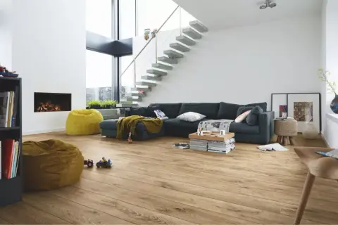 Salon moderne avec canapé, cheminée, poufs et escalier flottant. Le parquet flottant, d'une épaisseur idéale, réchauffe l'espace.