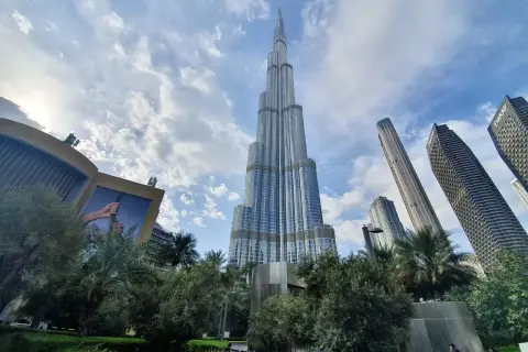 Majestatyczny Burj Khalifa w Dubaju wznosi się ku niebu, otoczony nowoczesnymi wieżowcami i zielenią.