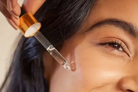Kropla serum z pipetki zbliża się do twarzy, obiecując widoczne retinol efekty.