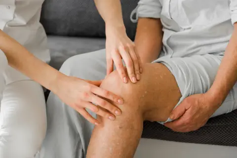 Lekarz bada nogę pacjenta z widocznymi żylakami. Czy skleroterapia jest bezpieczna? To pytanie nurtuje wiele osób.