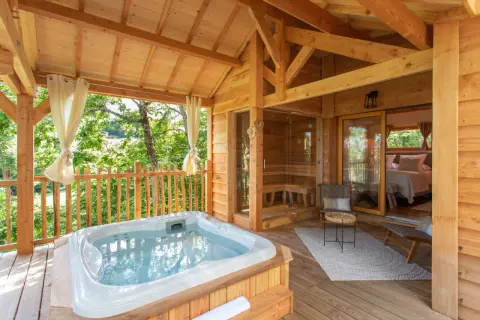 Terrasse en bois avec jacuzzi, sauna et chambre. Une invitation à une nuit insolite au nord, au cœur de la nature.