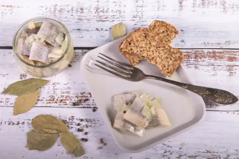 Śledzie z cebulką i chlebem na talerzu. Pytanie, czy w Wielki Piątek można jeść mięso, nie dotyczy tej potrawy.