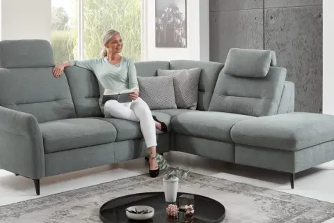 Frau liest auf einem gemütlichen Ecksofa mit verstellbaren Kopfstützen. Die tiefe **sitztiefe sofa** lädt zum Entspannen ein.
