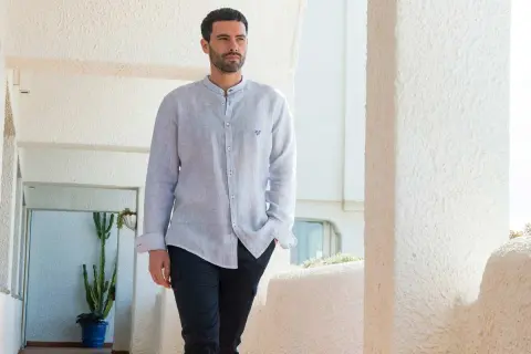 Uomo con camicia a maniche lunghe, dal taglio comodo, con la **lunghezza camicia uomo fuori pantaloni** che crea un look casual.