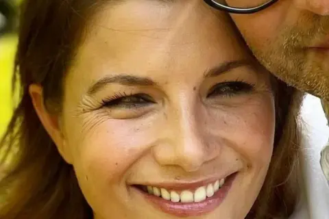 Agnieszka Sienkiewicz uśmiecha się, przytulona do swojego męża, który ma zarost i okulary.