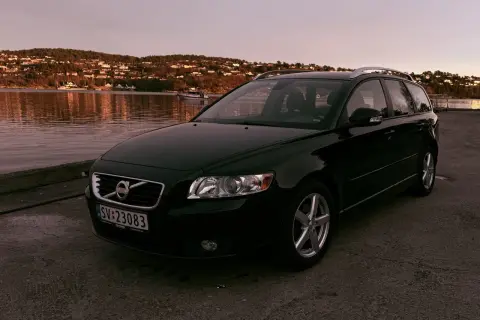 Svart Volvo V50 vid vattnet i solnedgången. Denna bilmodell är känd för sina pålitliga volvo v50 motorer.