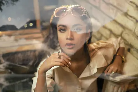 Jeune femme au regard intense, lunettes sur la tête, avec un effet vitre photoshop créant une atmosphère rêveuse.