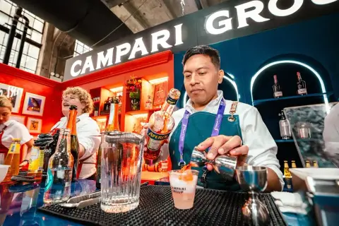 Barman przygotowuje drinka z Aperol. W tle widać logo Campari Group.