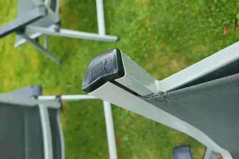 Nahaufnahme eines beschädigten Gartenstuhl PVC Bespannung. Die Reparatur ist dringend nötig, um den Stuhl wieder nutzbar zu machen.