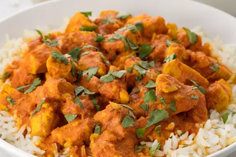 En skål med fluffigt ris toppad med saftig kyckling i en krämig, orange currysås. Strössel av färsk koriander ger en härlig touch till denna skolans kyckling curry.