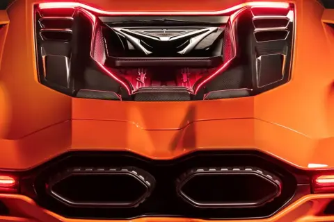 Pomarańczowy Lamborghini Revuelto z widocznym silnikiem i czerwonym podświetleniem.