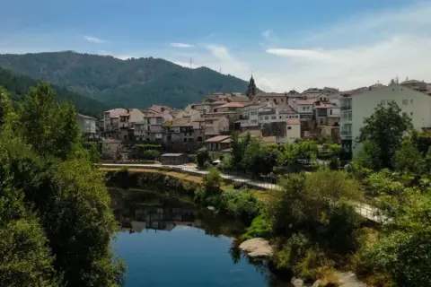 Un pueblo con tejados rojos y casas blancas se alza sobre un río tranquilo. Un lugar perfecto para descubrir qué ver en Ribadavia.