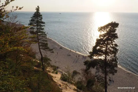 Zachód słońca nad Bałtykiem, złocący piaszczystą plażę i majestatyczne klify na wyspie Wolin.