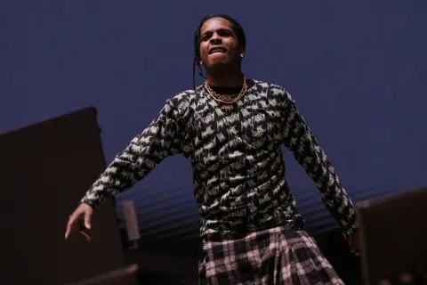 ASAP Rocky opener na scenie, w bluzie z nadrukiem i kratową spódnicą.