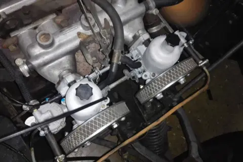 Detalle del motor de un coche clásico con doble carburador, listo para dar potencia.