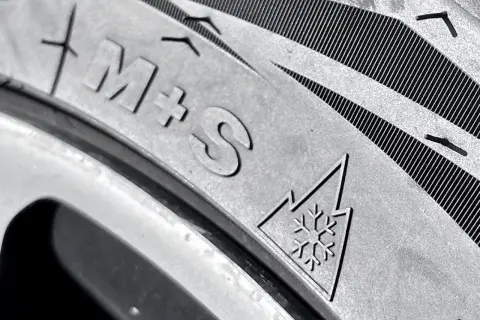 Nahaufnahme eines Reifens mit "M+S"-Kennzeichnung und dem Schneeflockensymbol, das auf Winterreifen hinweist.