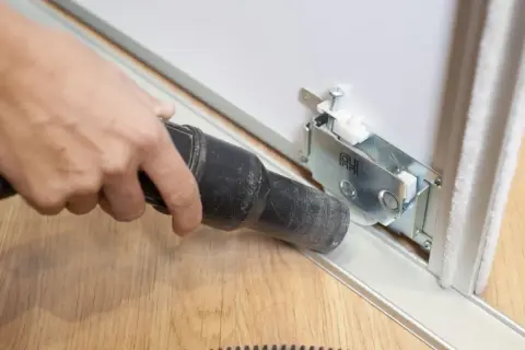 Limpia el riel de un armario corredero con una aspiradora para ajustar puertas armario.