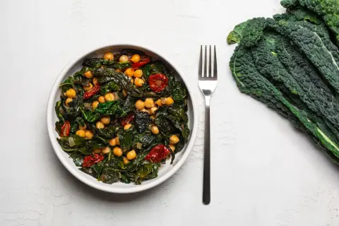 Piatto invitante con cavolo nero, ceci e pomodorini secchi, un'idea per una cavolo nero ricetta sana e gustosa.