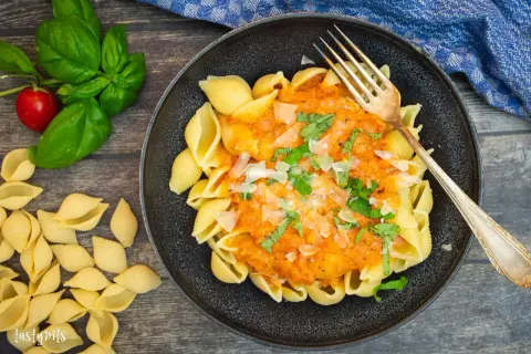 Schalen-Nudeln mit cremiger Tomaten-Sahne-Sauce, garniert mit Basilikum und Parmesan. Ein Genuss!