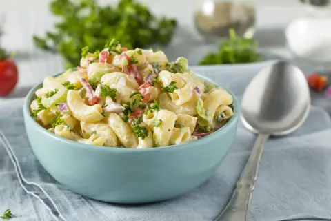 Cremiger Nudelsalat mit Joghurt, garniert mit frischer Petersilie. Perfekt für ein leichtes Mittagessen.