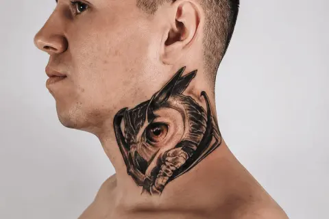 Ein Mann trägt ein detailreiches Eulen-Hals-Tattoo, das wie ein Mandala wirkt.