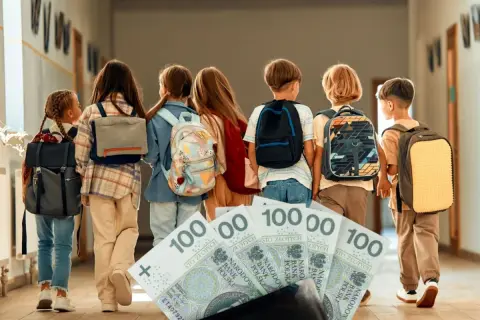 Dzieci z plecakami idą korytarzem, a przed nimi leżą banknoty 100 zł. Zastanawiamy się, ile szkoła dostaje za dziecko z orzeczeniem.